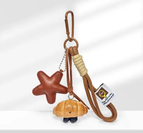 Handmade soda bread creative style handbag pendant with a 5cm diameter, featuring a cartoon croissant design and a 30cm brown carrying strap for easy attachment to bags.