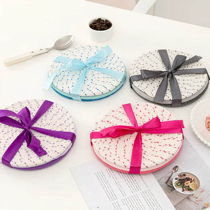 Set of three round grey cotton cord coasters, each 18cm in diameter, on a wooden table.