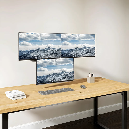 Black aluminium three-arm gas spring monitor holder mounted on a desk edge.