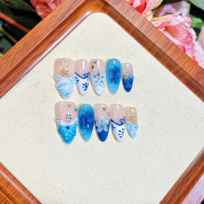 Set of 24 blue hand-painted false nails with carved floral design on transparent base, showing XS, S, M, L sizes.