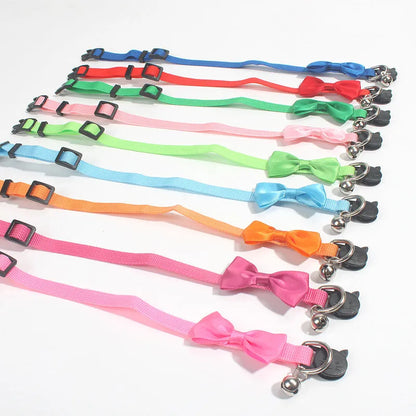 Striped nylon cat collar with decorative bow and bell in multiple colour options on a white background.