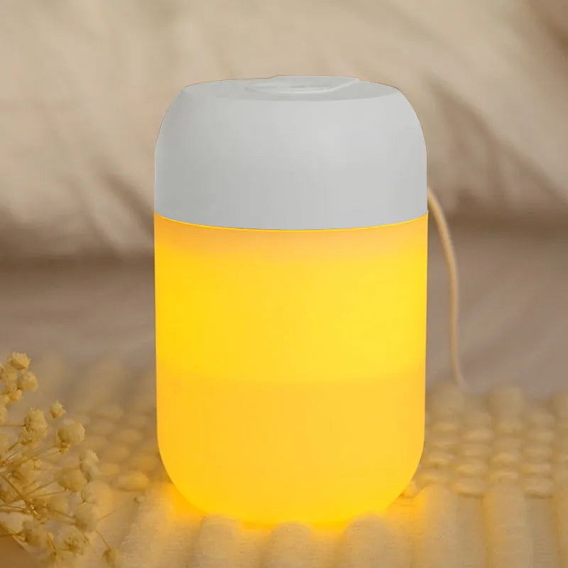 White cylindrical humidifier with USB cable on a desk, showing compact 15cm height and aromatherapy function for essential oils.