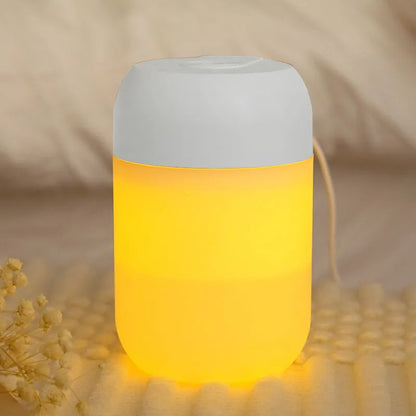 White cylindrical humidifier with USB cable on a desk, showing compact 15cm height and aromatherapy function for essential oils.