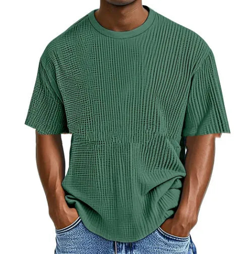 Man wearing a light blue waffle-textured cotton blend short sleeve t-shirt, casual pullover style.