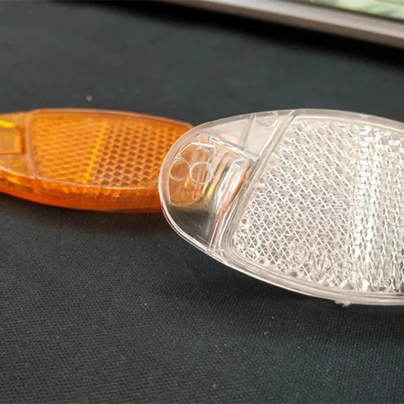 Four white bicycle spoke reflectors showing dimensions of 7.2cm by 3.5cm