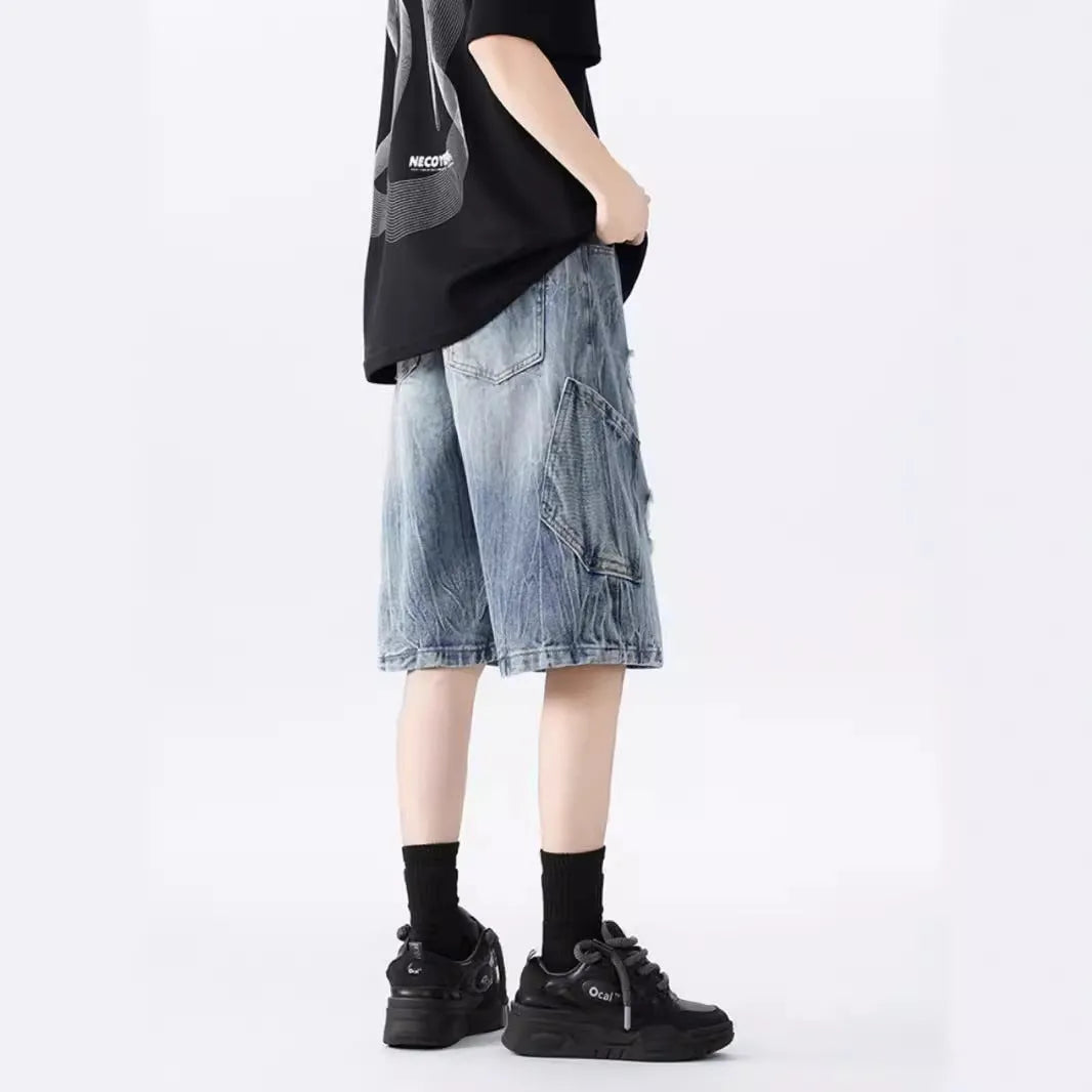 Man wearing loose fit black ripped denim shorts with distressed detailing and a washed vintage finish.