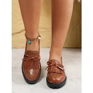 Women's black slip-on loafer shoe with a decorative bow on the front.