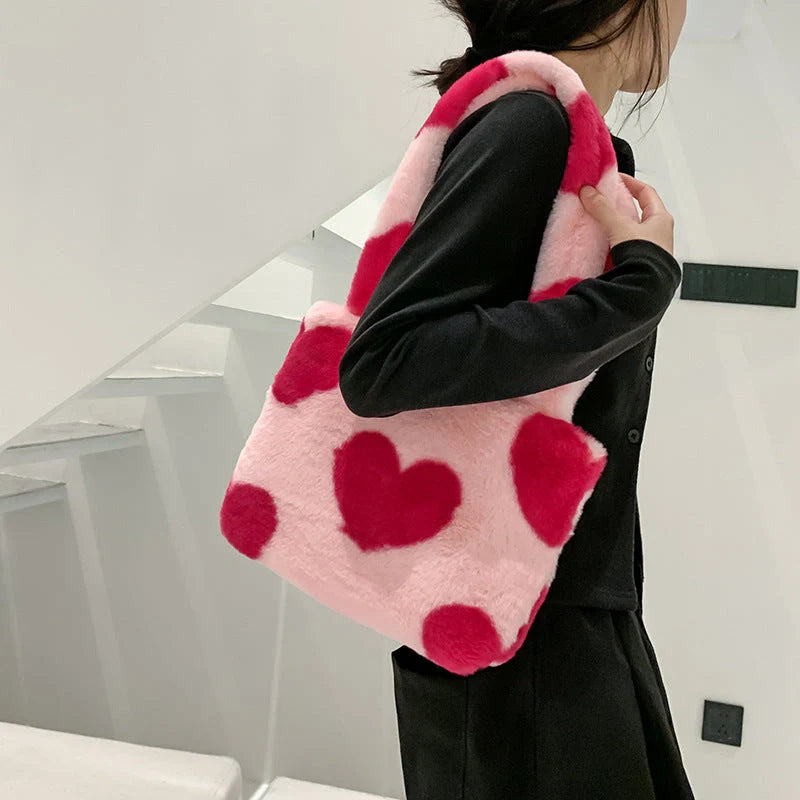 Soft, plush heart-shaped handbag in various vibrant colors with a magnetic closure and interior phone compartment