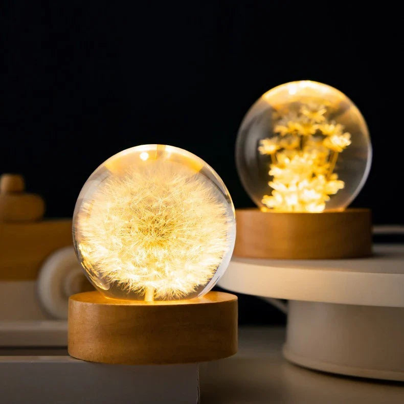 Enchanting 3D dandelion, yellow daisy, or red daisy flowers suspended in a clear crystal ball with a beech wood base, creating a mesmerizing desktop decor piece.