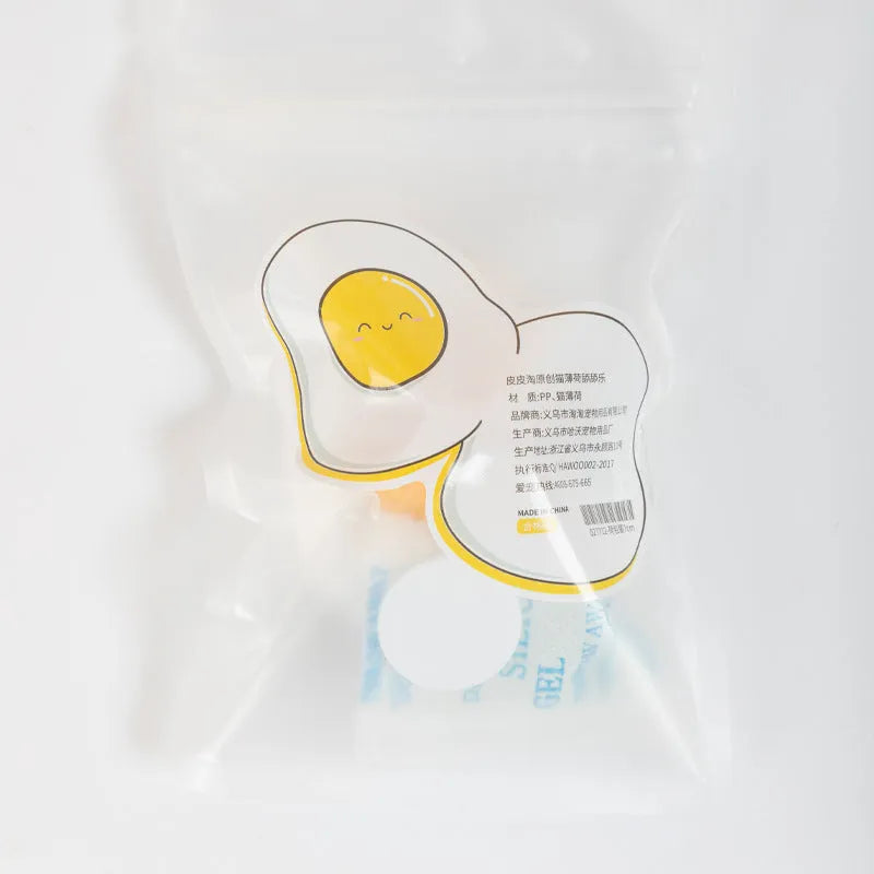 Interactive plush catnip ball toy shaped like a fried egg, stuck to a wall with a cat batting at it.