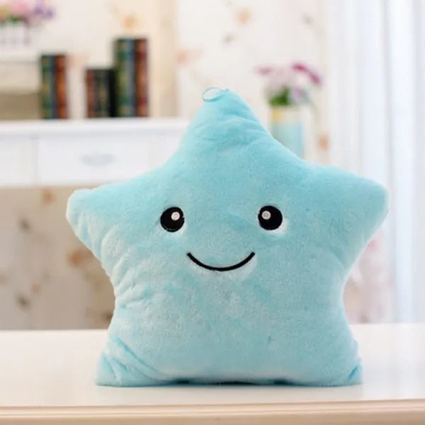 Colourful glowing five-pointed star plush pillow on a dark background.