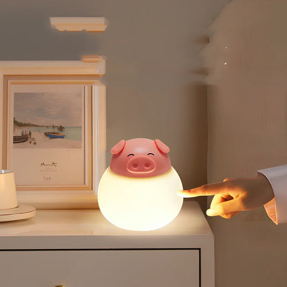 Pink silicone pig-shaped bedside lamp with adjustable lighting on wooden table