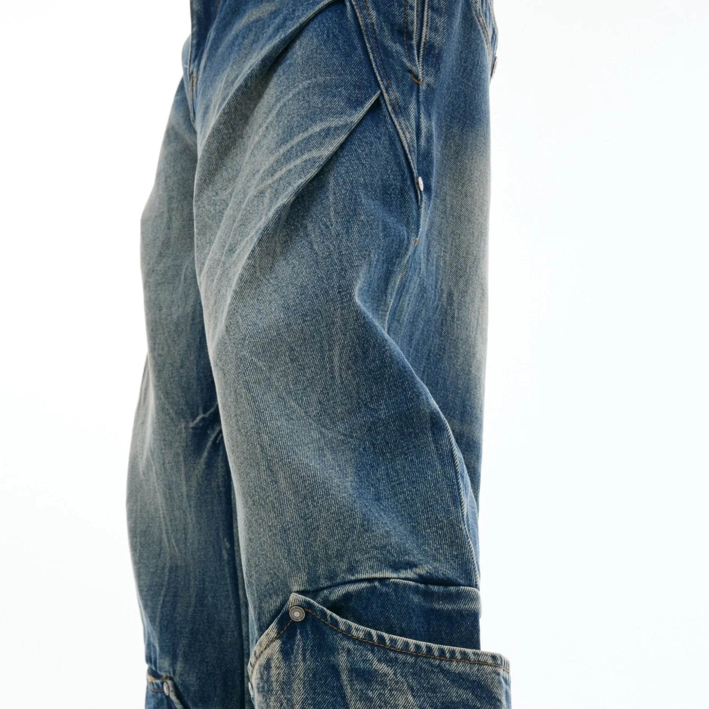 Men's verdant blue jeans with washed burst pattern and curved knife design, showing loose fit and retro style.
