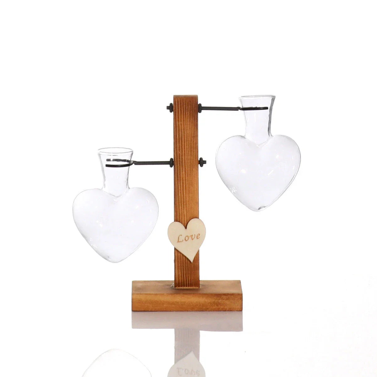 Elegant heart-shaped glass terrarium with wooden stand, showcasing a natural, minimalist design perfect for indoor plant display or decorative accents.