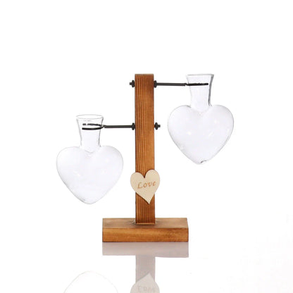 Elegant heart-shaped glass terrarium with wooden stand, showcasing a natural, minimalist design perfect for indoor plant display or decorative accents.