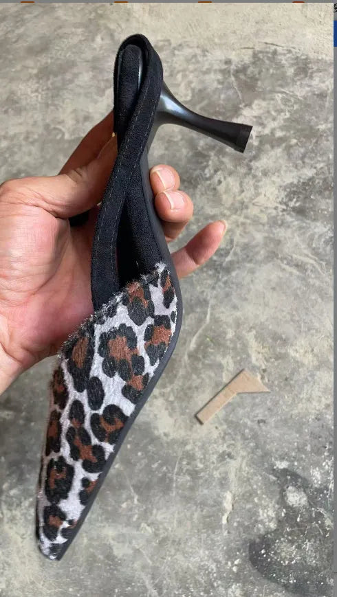 Leopard print suede women's sandals with a pointed toe high heel on a neutral background.