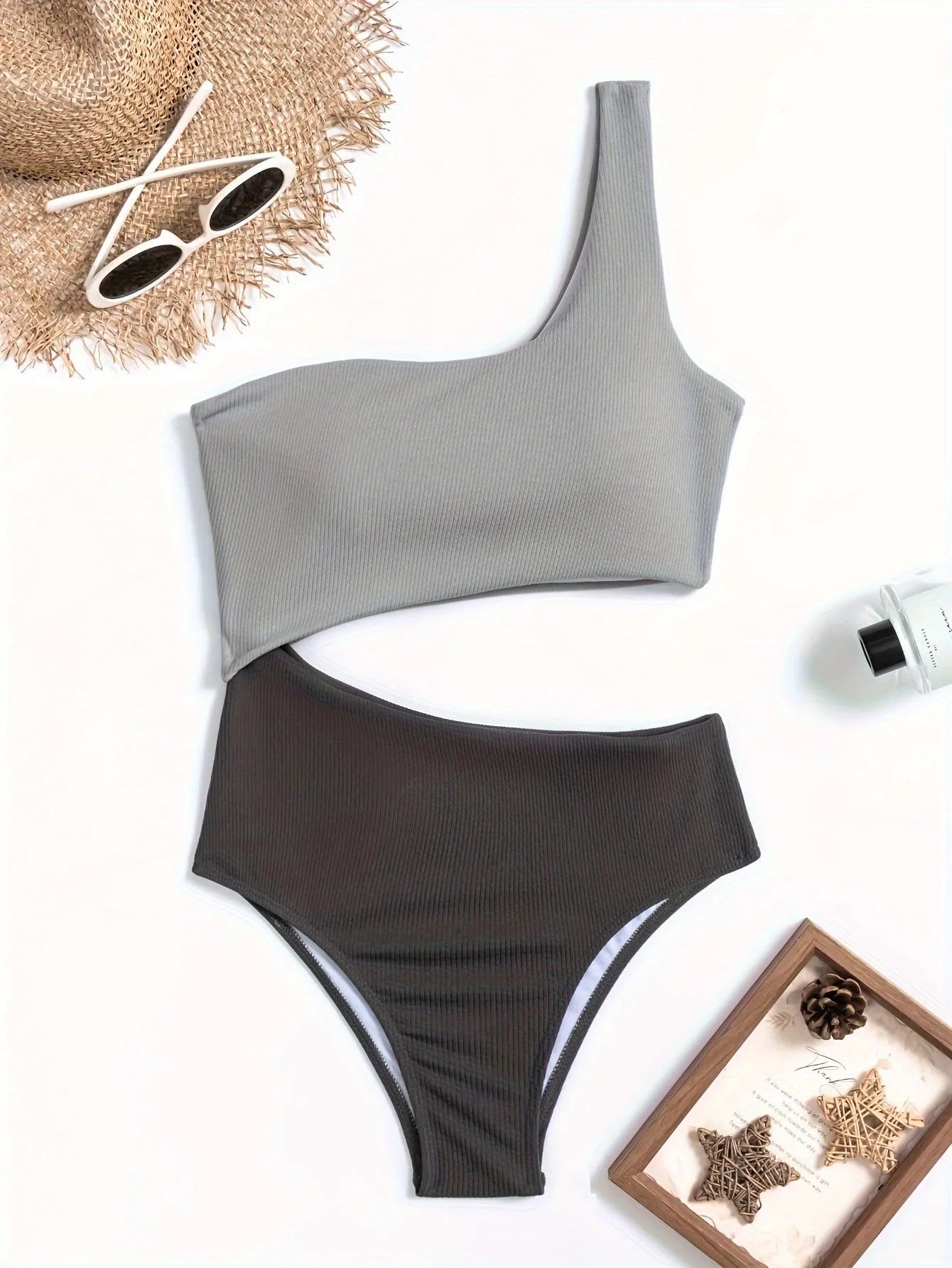 Women's light grey one-shoulder one-piece swimsuit made from polyester fabric.