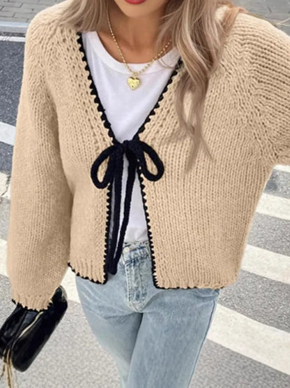 Loose grey lace-up front cardigan sweater with crocheted flower detail on a model.