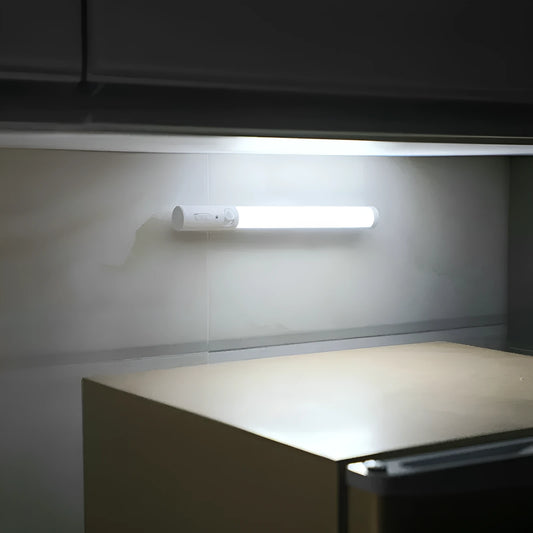 Slender white human body induction LED cabinet light with magnetic back for tool-free installation.