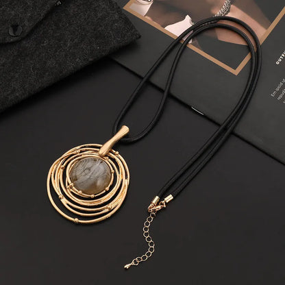 Gold geometric plaid pendant necklace on a textured snakeskin-style rope chain, laid out to show length.