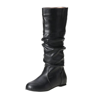 Women's flat slip-on boots in black with round toe and high cylinder shaft on a neutral background.