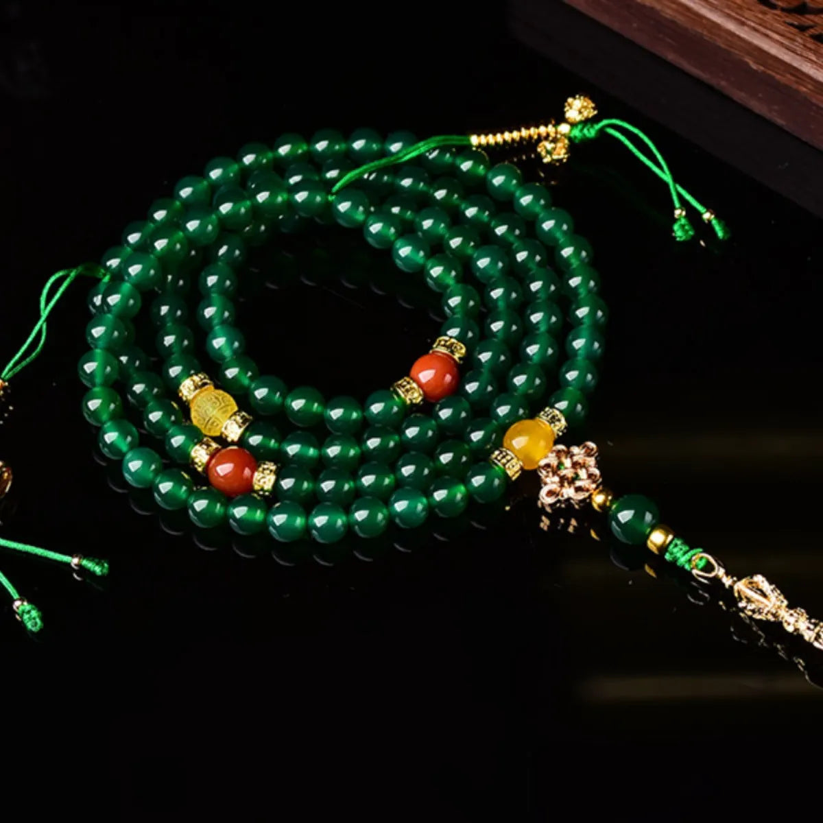 Close-up of a multi-strand green agate bracelet with natural stones on a wrist.