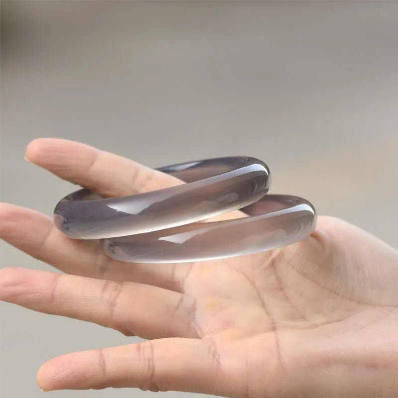A women's bracelet made from dark grey Brazilian iced chalcedony agate, showing circle and line design elements.