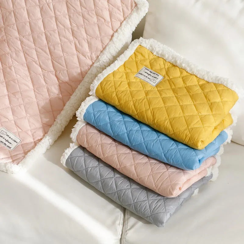Quilted terry cloth pet blanket for cats in blue, grey, pink, or yellow colour on a pet bed.