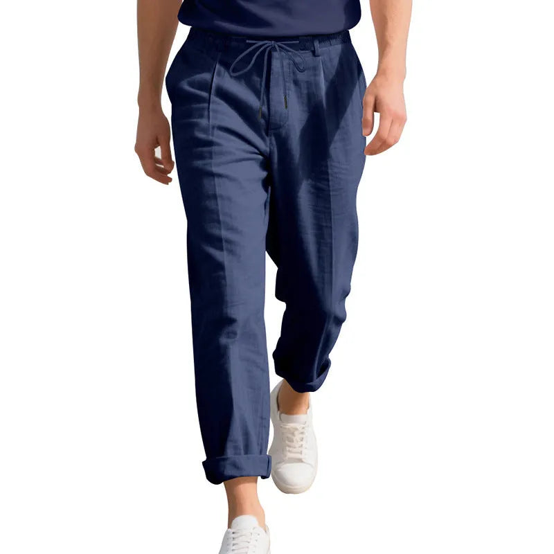 Men's light beige linen trousers with a loose straight leg and drawstring waist on a hanger.