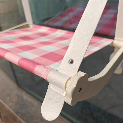 Pink cat hammock with wooden frame and suction cups attached to a window, with a cat resting inside.
