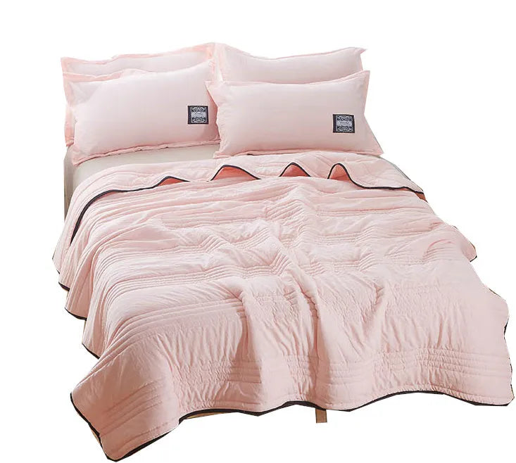 Lightweight plain coloured polyester summer quilt on a bed