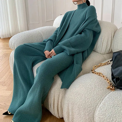 Women's knitted three-piece set with wide-leg trousers, cardigan, and top in solid colours, showing leather stitching details