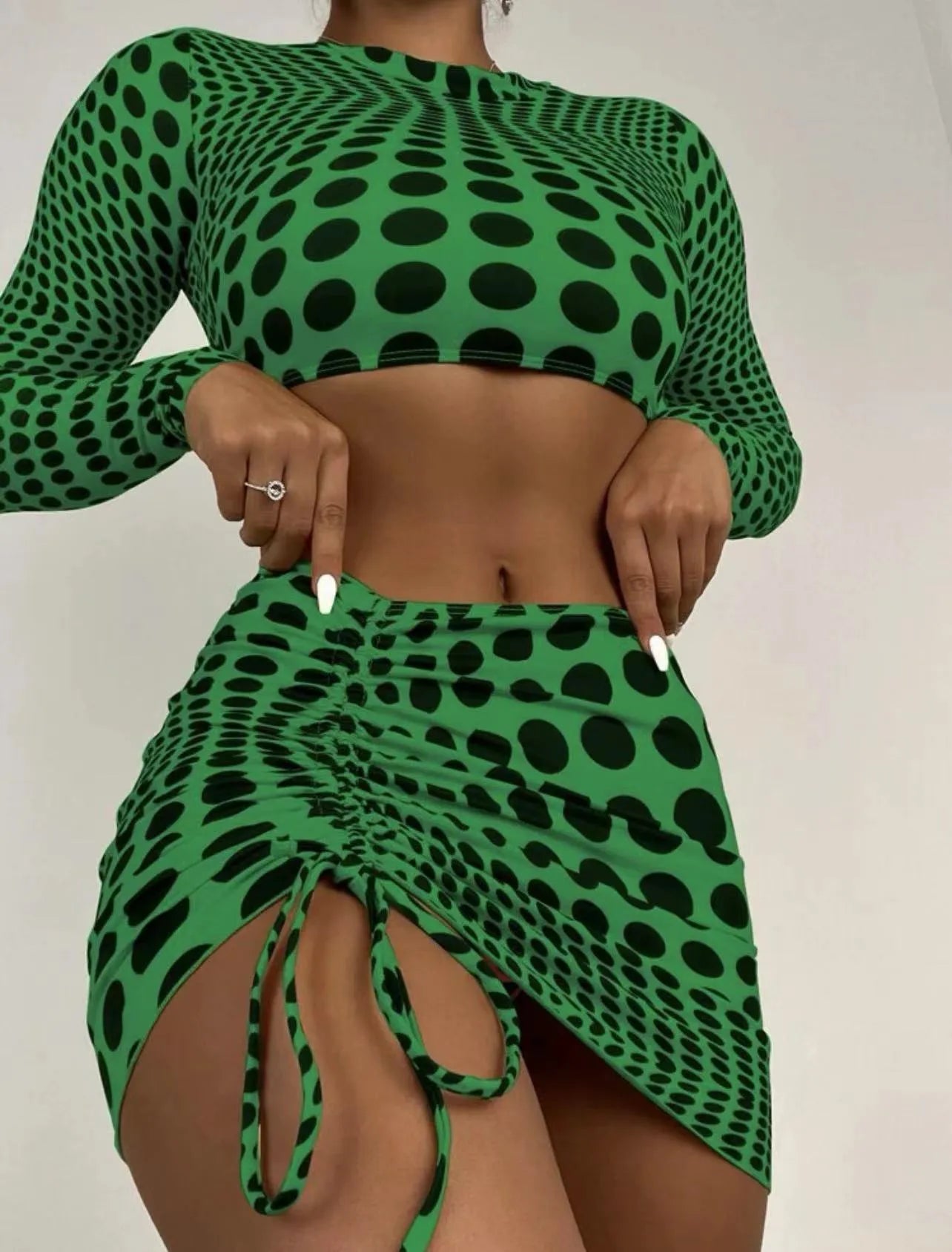 Green polka dot women's three-piece swimsuit set with top, skirt, and bra on hanger