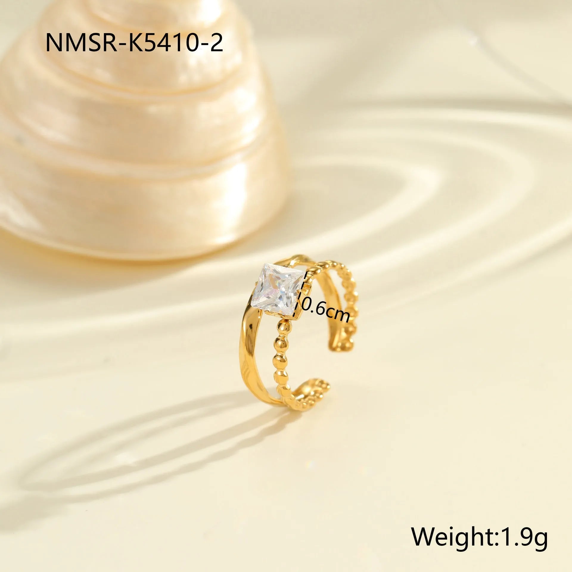 Gold electroplated stainless steel open mouth ring with geometric shapes and zircon inlay on a heart drop.