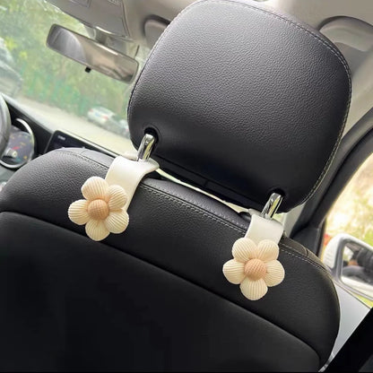 Khaki coloured plastic car seat hook with floral pattern for storage, shown at 11 by 5.5 cm.