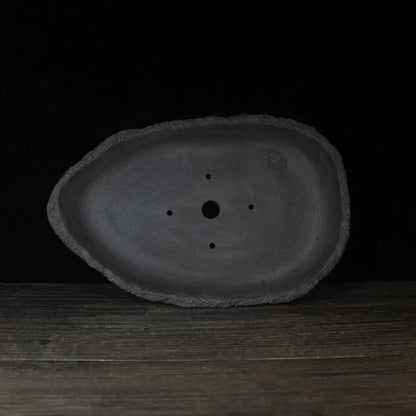 Handmade purple clay flower pot with unique shape showing natural ceramic texture