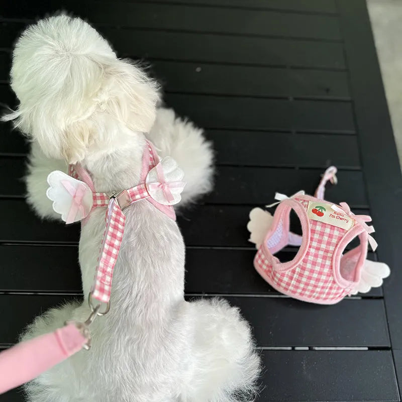 Small dog wearing adjustable cotton harness in pink with chest-back design and hand holding rope attachment