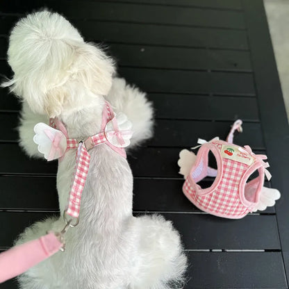 Small dog wearing adjustable cotton harness in pink with chest-back design and hand holding rope attachment