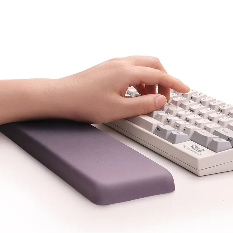 Square cloth mouse pad with grey silicone gel wrist rest and hand pillow on a wooden desk.