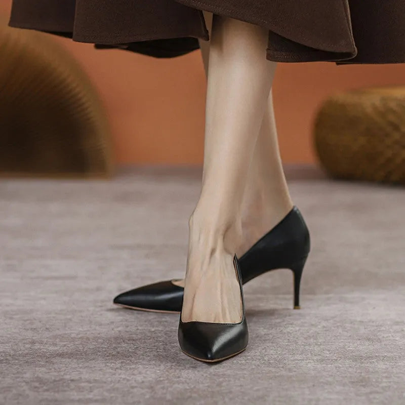 Black pointed toe stiletto high heel shoe with a low cut vamp on a white background.
