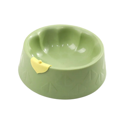Green plastic double pet bowl with two compartments for food and water on a flat surface.
