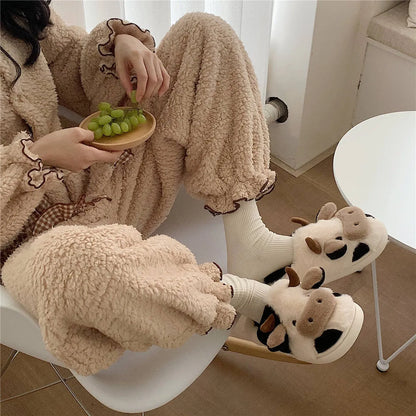 White cow-themed plush slippers with a non-slip textured sole for women.