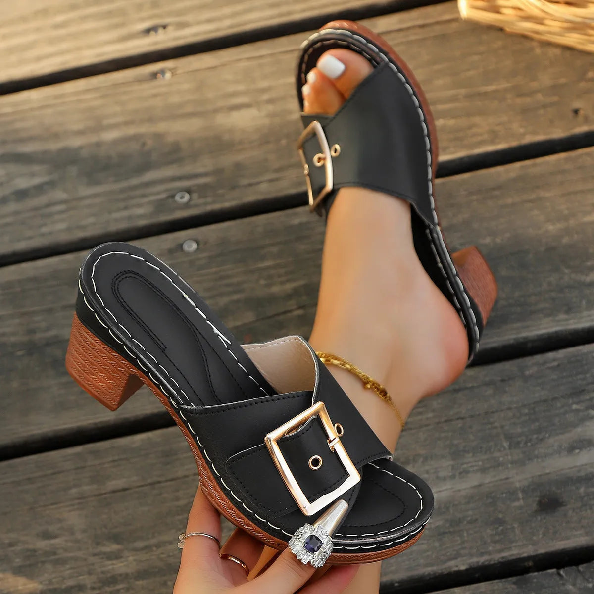 Women's black chunky heel slippers with a metal buckle on the strap and a rubber sole.
