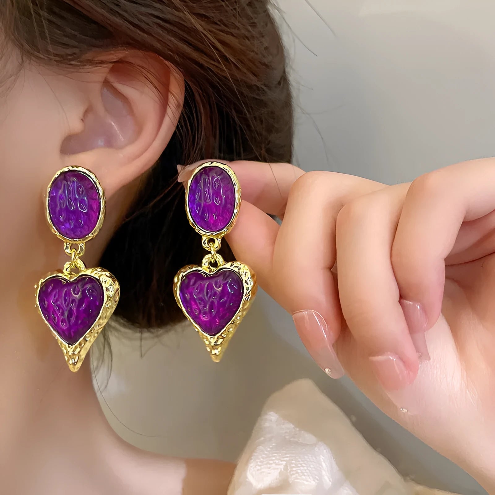 A pair of silver-tone stud earrings with a textured pleated oval love heart shape in various colour options.