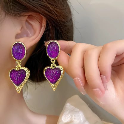 A pair of silver-tone stud earrings with a textured pleated oval love heart shape in various colour options.