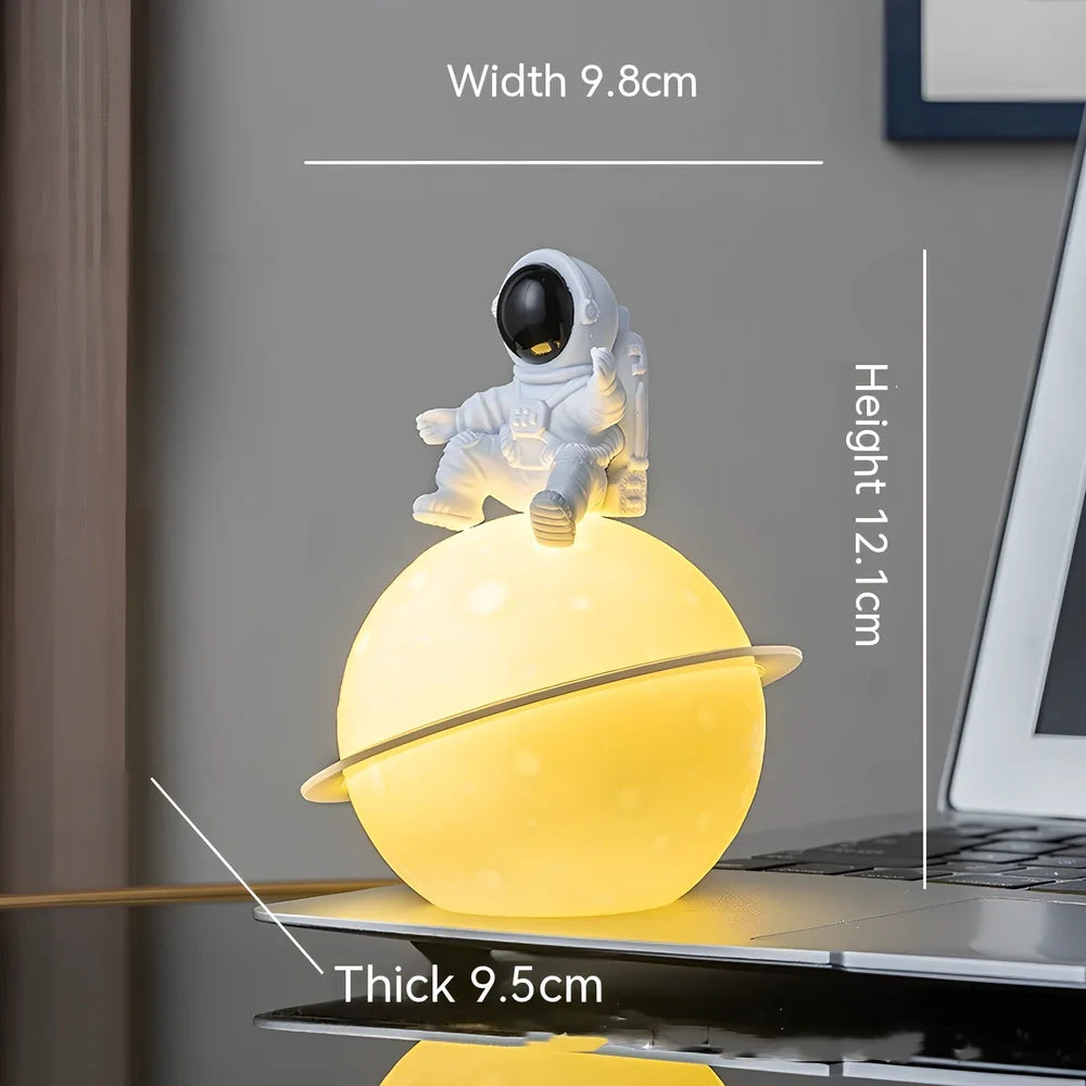Astronaut planet night lamp in golden finish, 12 cm tall PVC ABS figure with glowing 3 cm orb on 5 cm base