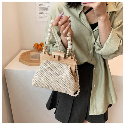 Women's beige straw woven shoulder bag with pearl chain strap, showing horizontal square shape and sewing line detail.
