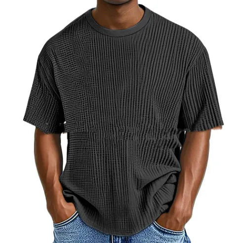 Man wearing a light blue waffle-textured cotton blend short sleeve t-shirt, casual pullover style.