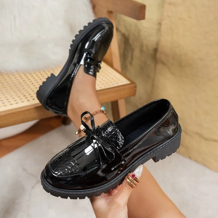Women's black slip-on loafer shoe with a decorative bow on the front.