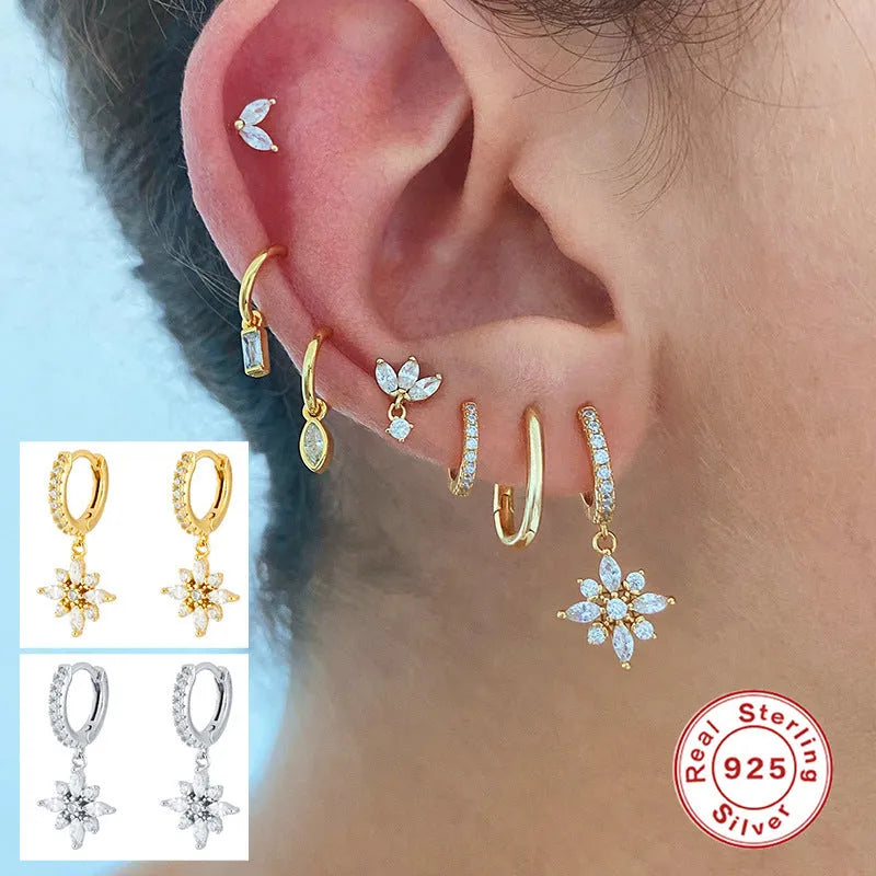 A pair of sterling silver snowflake pendant earrings with cubic zirconia stones on a white background.